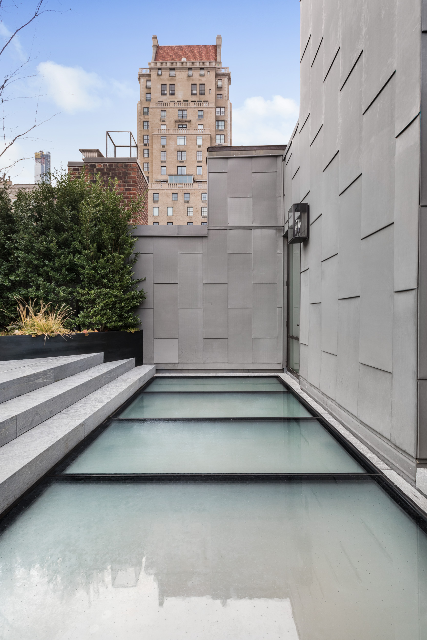Modern rooftop area featuring circular skylights with a city view in the background.