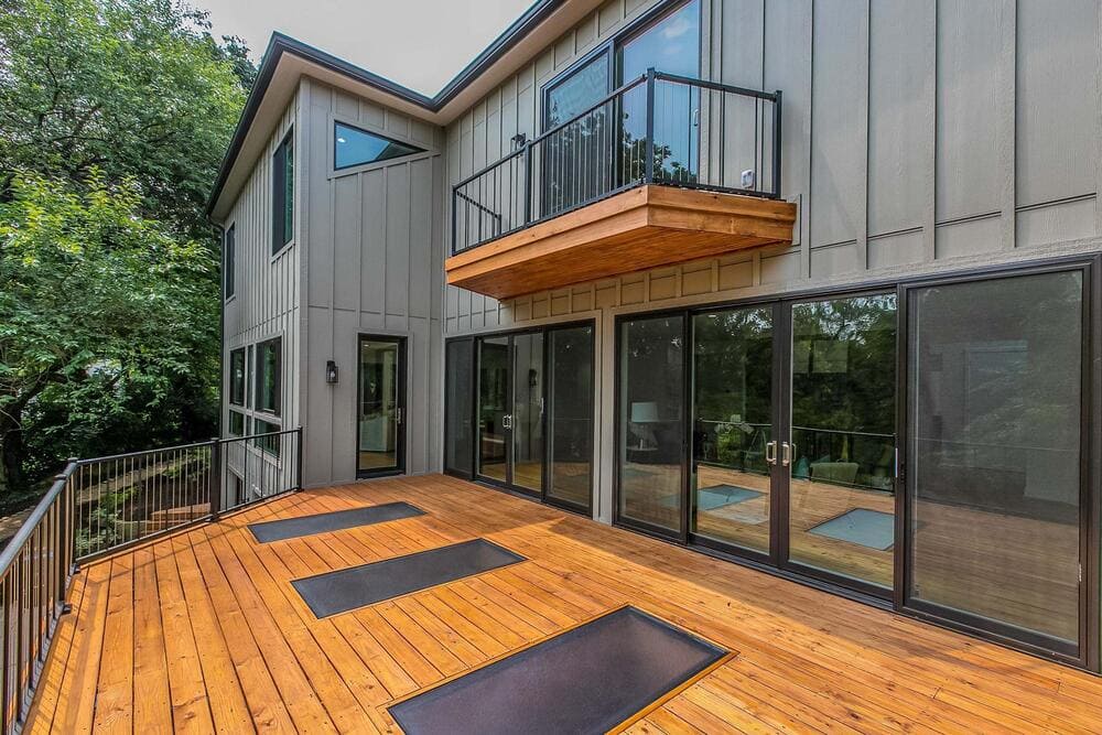 Contemporary house with a wooden deck and large glass sliding doors overlooking the backyard.