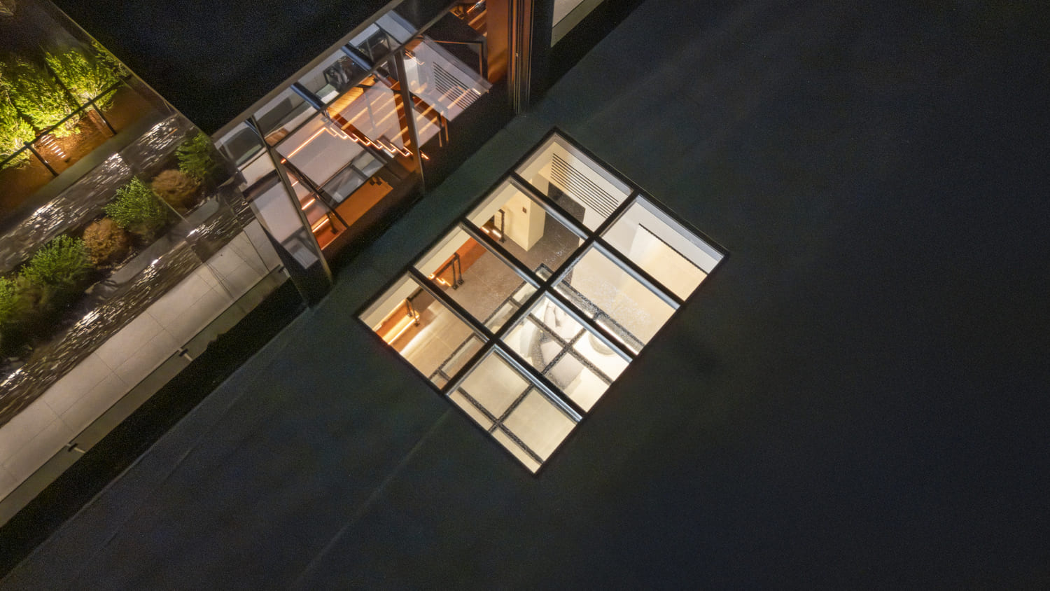 Top-down nighttime view of large commercial skylights installed on a flat roof.