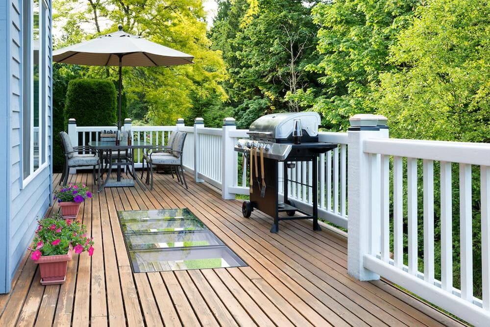 Timber deck with walkable glass inserts surrounded by outdoor seating and garden plants.