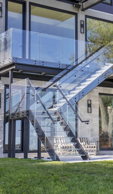 Three-story home with multiple glass patio decks and staircases offering open, scenic outdoor living.