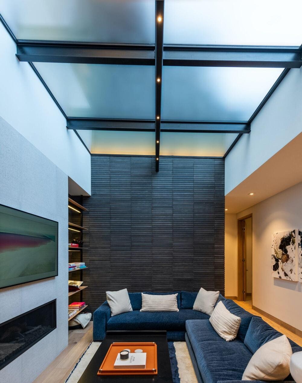 Luxurious indoor lounge with tall glass walls and overhead skylight panels allowing natural light in.
