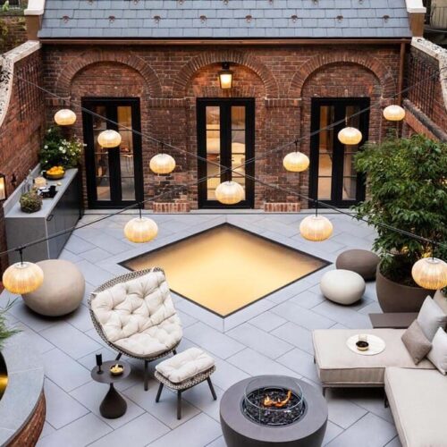 Cozy brick patio with fire pit surrounded by outdoor seating and plants.