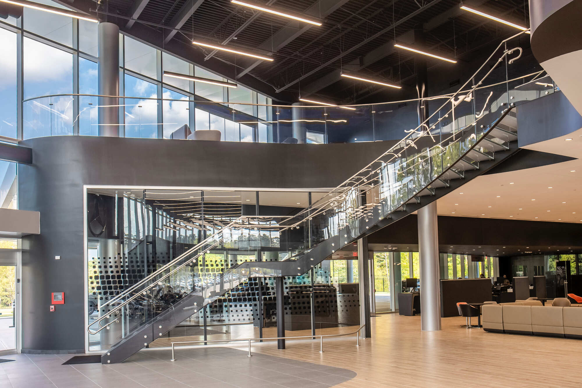 Large commercial glass staircase inside a modern lobby with open seating areas.