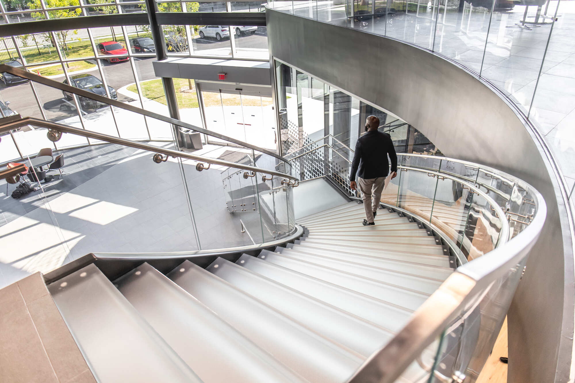 Curved glass staircase with clear treads and glass balustrades inside a modern public building.