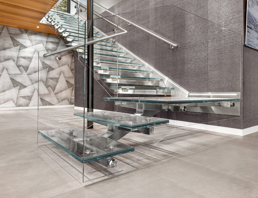 Contemporary interior featuring a cantilevered glass staircase with transparent treads and metal framing.