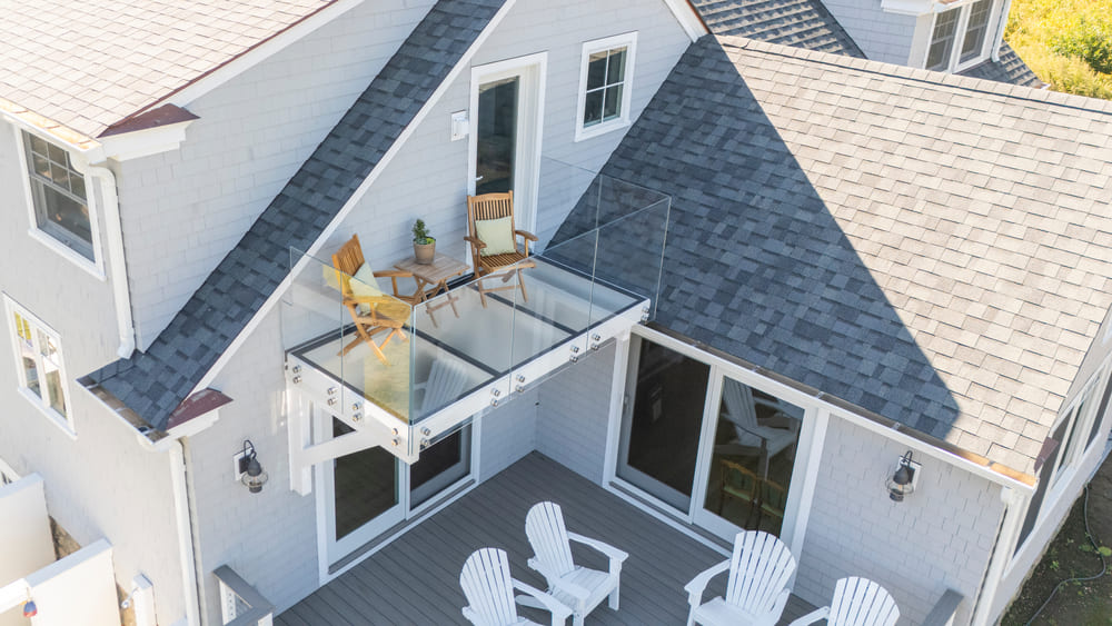 Aerial view of a home showcasing a glass deck with outdoor seating and transparent flooring.