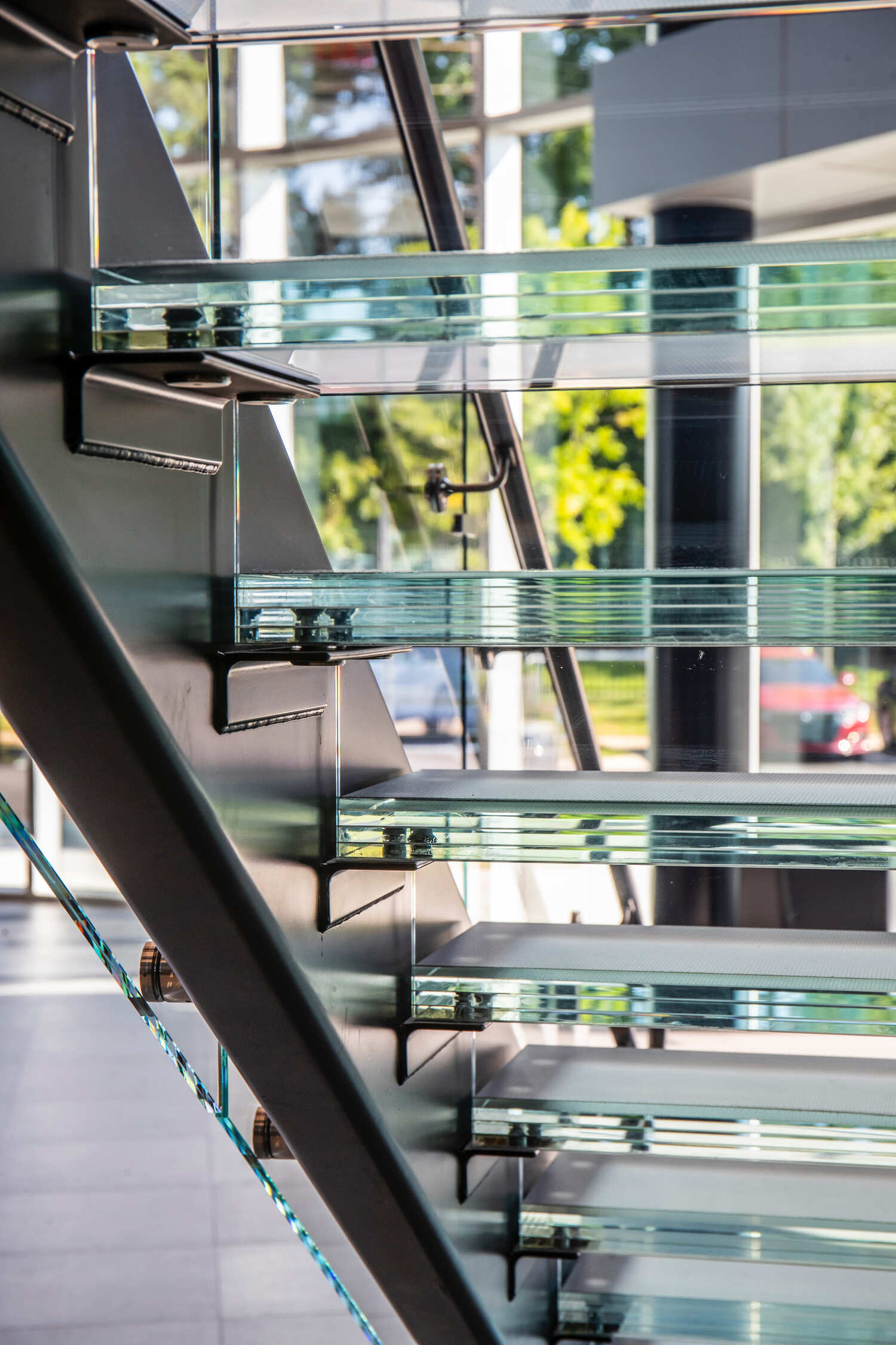 Glass stairwell viewed from the side, showcasing transparent stair treads and structural glass panels.