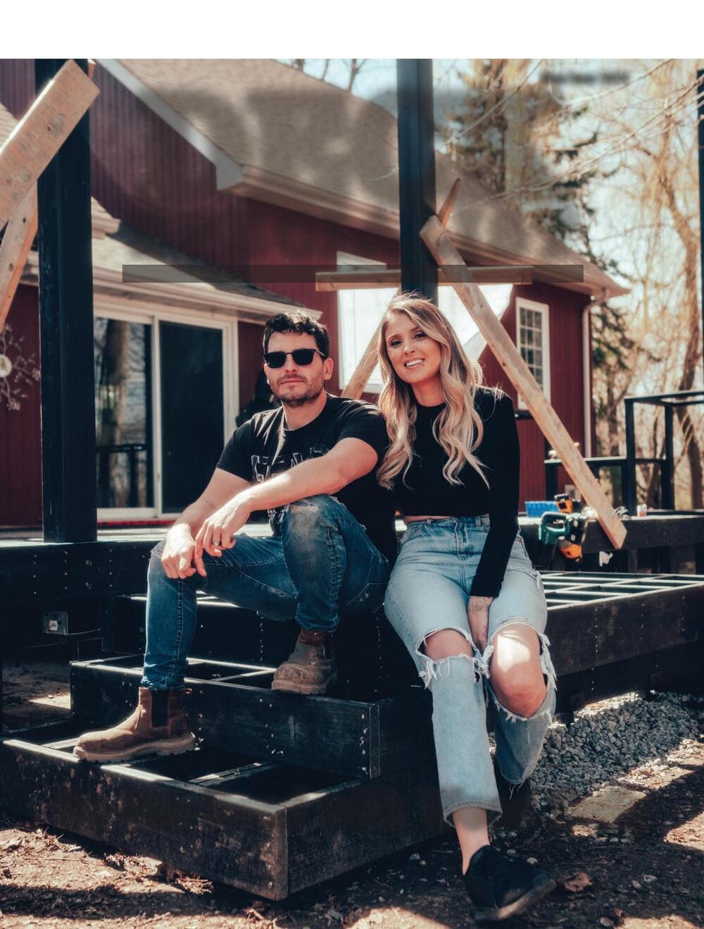 Couple sitting outdoors on a wooden staircase with laminated glass panels in the background.