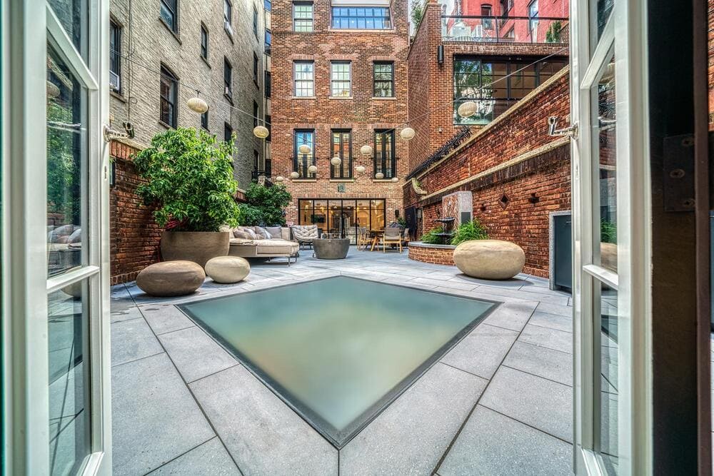 Outdoor rooftop patio with glass flooring panels overlooking a landscaped courtyard.