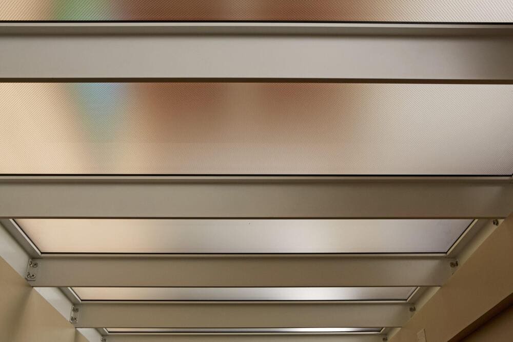 Glass ceiling panel system installed above an indoor seating area.