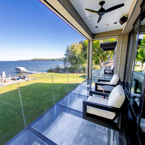 A glass veranda overlooking a wide backyard and the ocean.