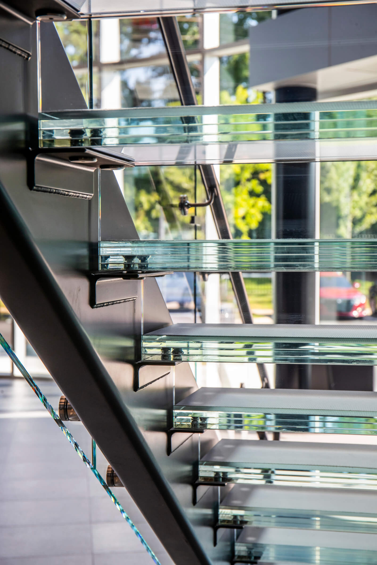 Glass stairwell viewed from the side, showcasing transparent stair treads and structural glass panels.