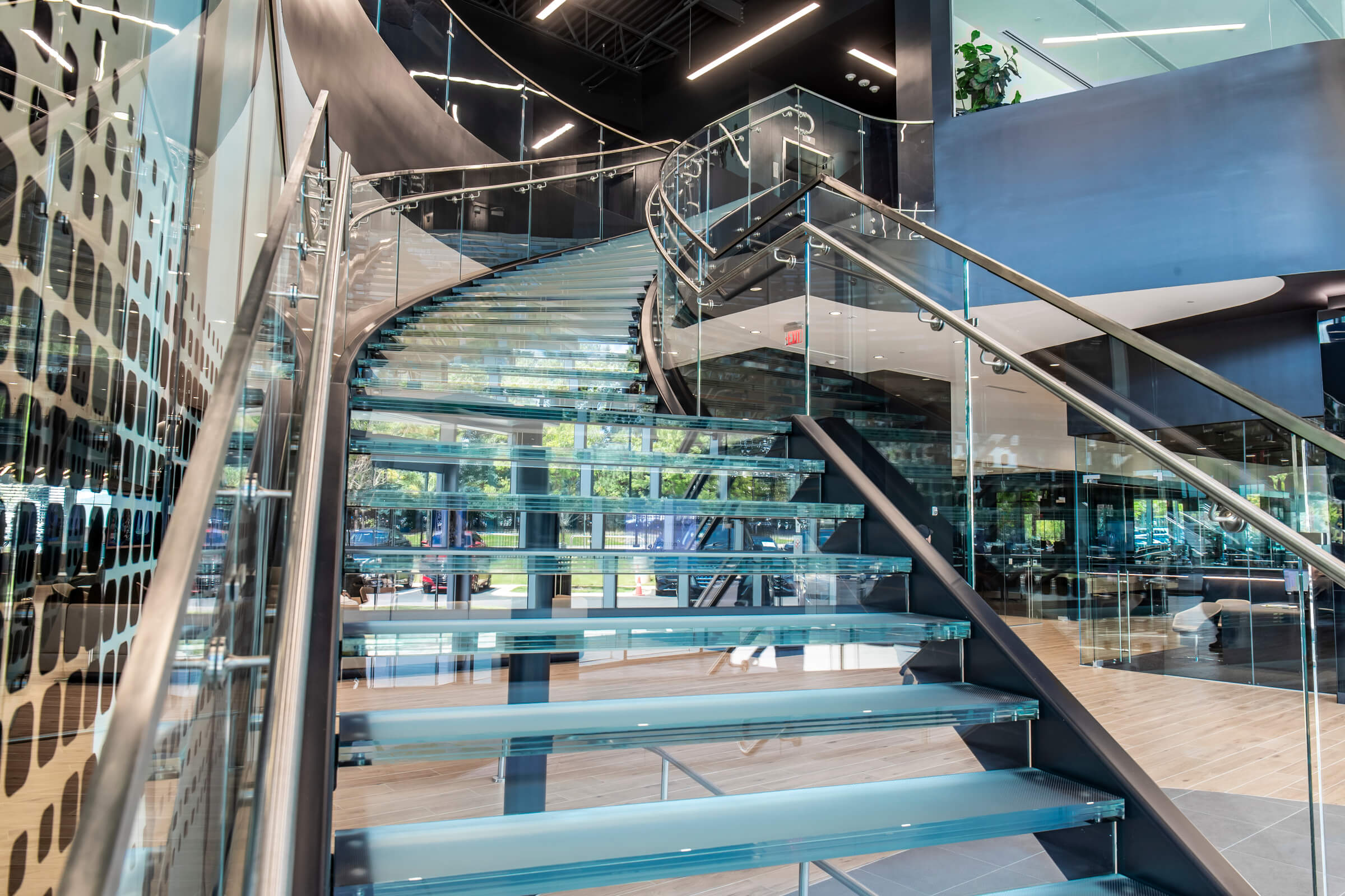 Large spiral glass staircase inside a bright, open atrium.
