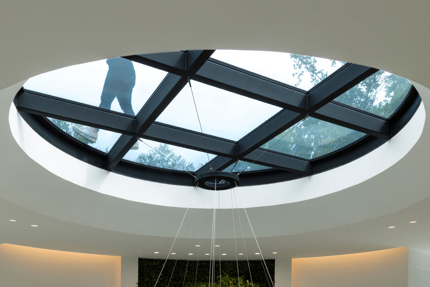 A modern stairwell framed with glass and a skylight ceiling in the middle.