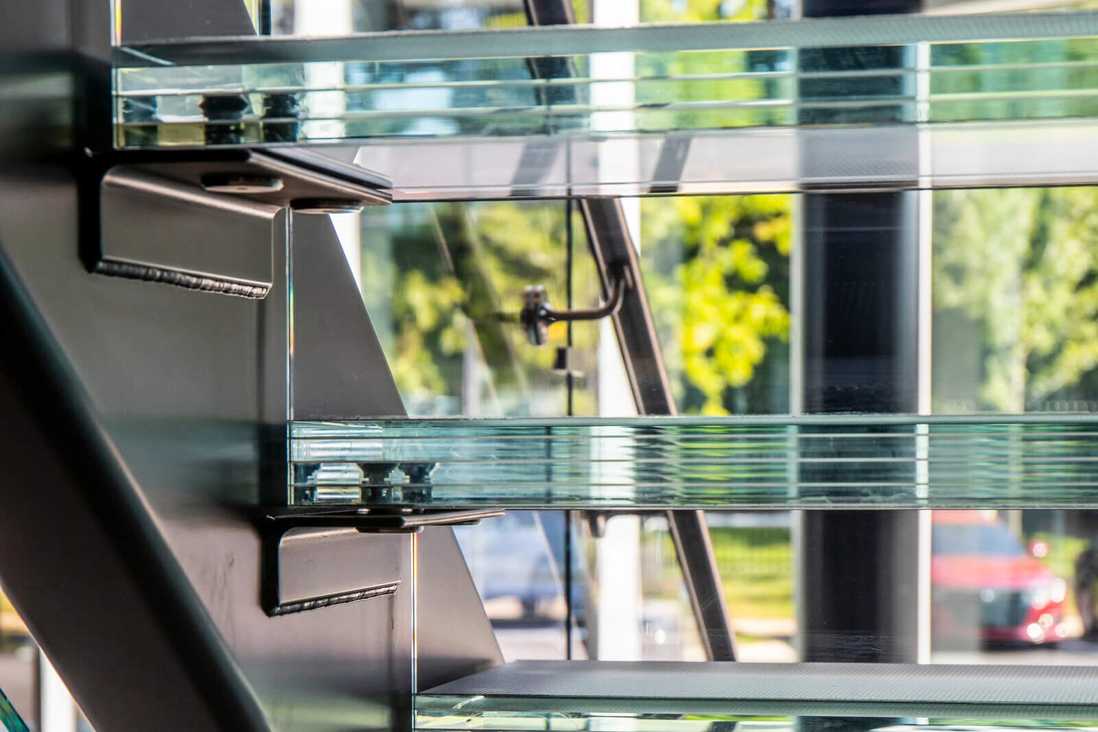 Glass stairwell viewed from the side, showcasing transparent stair treads and structural glass panels.
