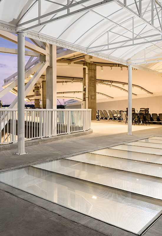 Modern covered deck with multiple glass floor panels in a bright open structure.