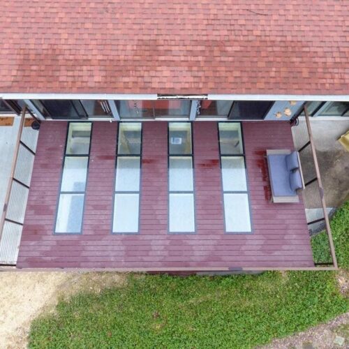 Top-down drone view of a wooden deck with five rectangular glass floor panels installed in a row.