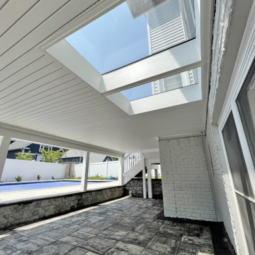 Patio below a deck with two walkable glass deck panels overhead, adding natural daylight to the space below.