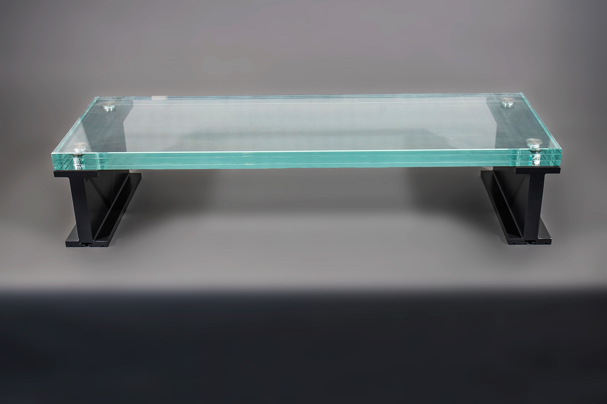 Full view of a laminated glass stair tread with a NanoDot® anti-slip surface, polished edges, titanium embedded fasteners, and black aluminum support frames.