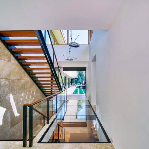 Modern staircase area with a glass floor walkway and white walls.
