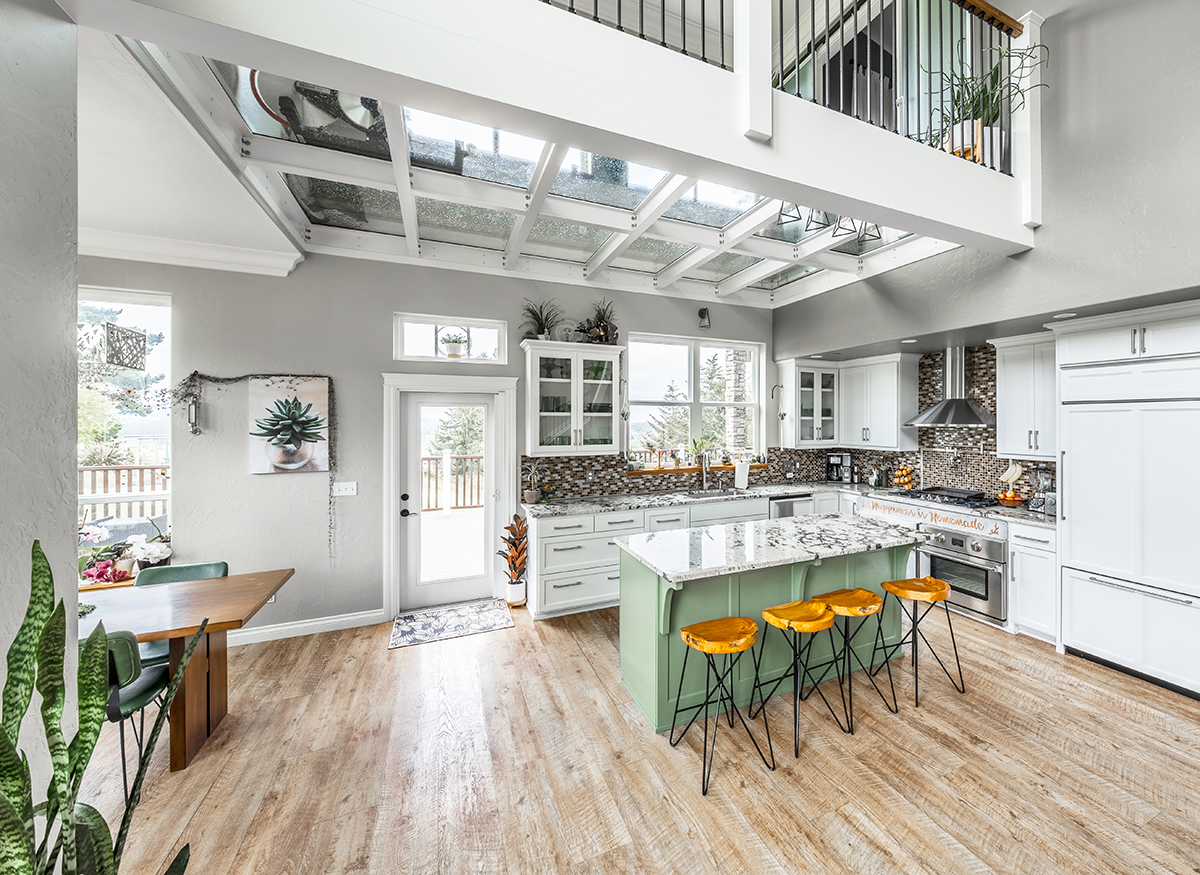 A kitchen with sustainable hardwood floors with a loft above the kitchen made of walkable glass floors that let light shine through into the space below.