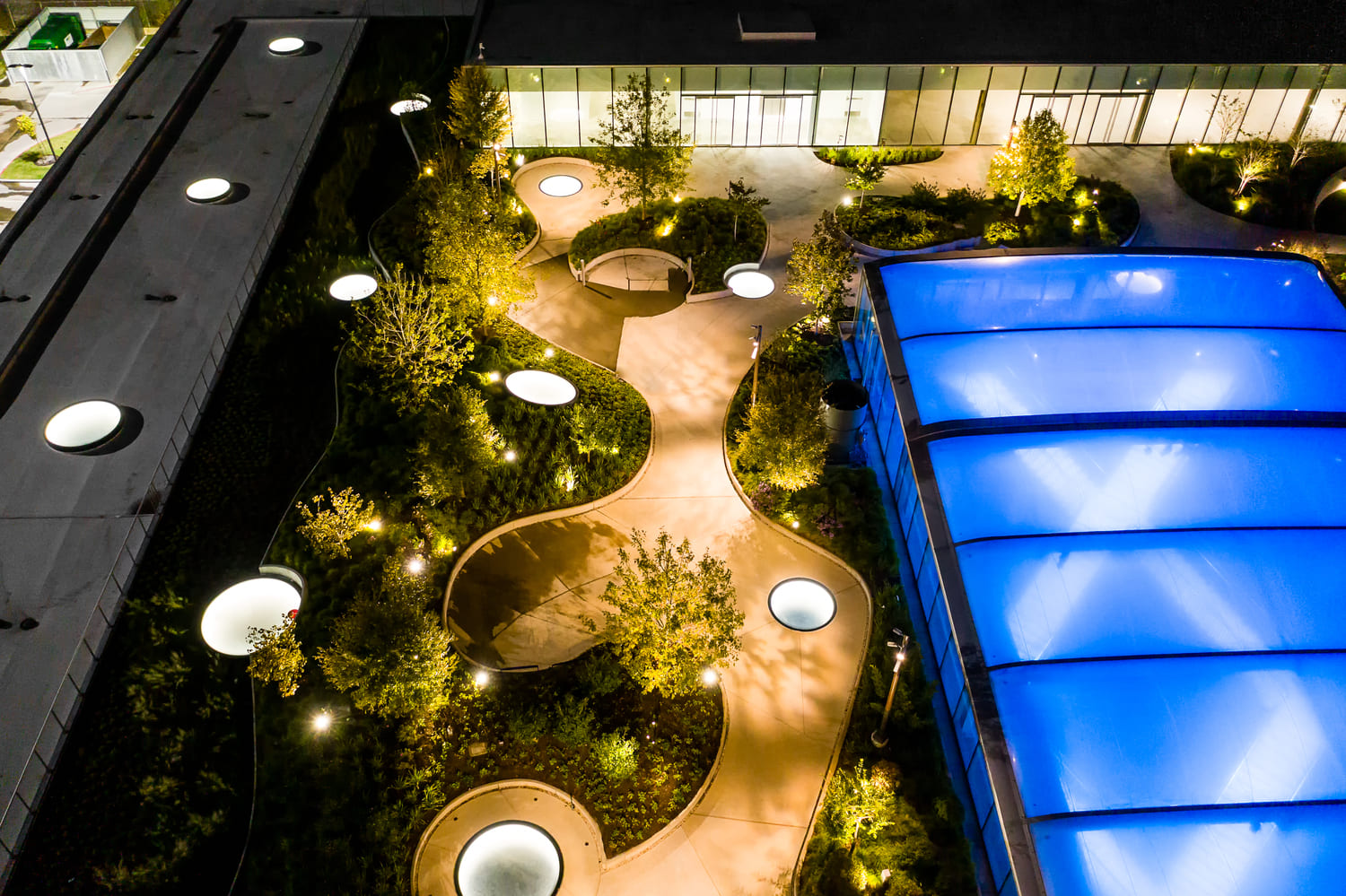 Rooftop garden at night with circular and rectangular lit SkyFloor walkable skylights