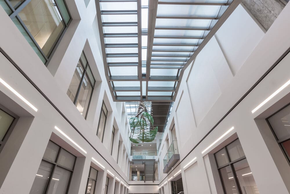 a modern hotel with a glass staircase connecting the floors with a clear glass railing and fall protection system