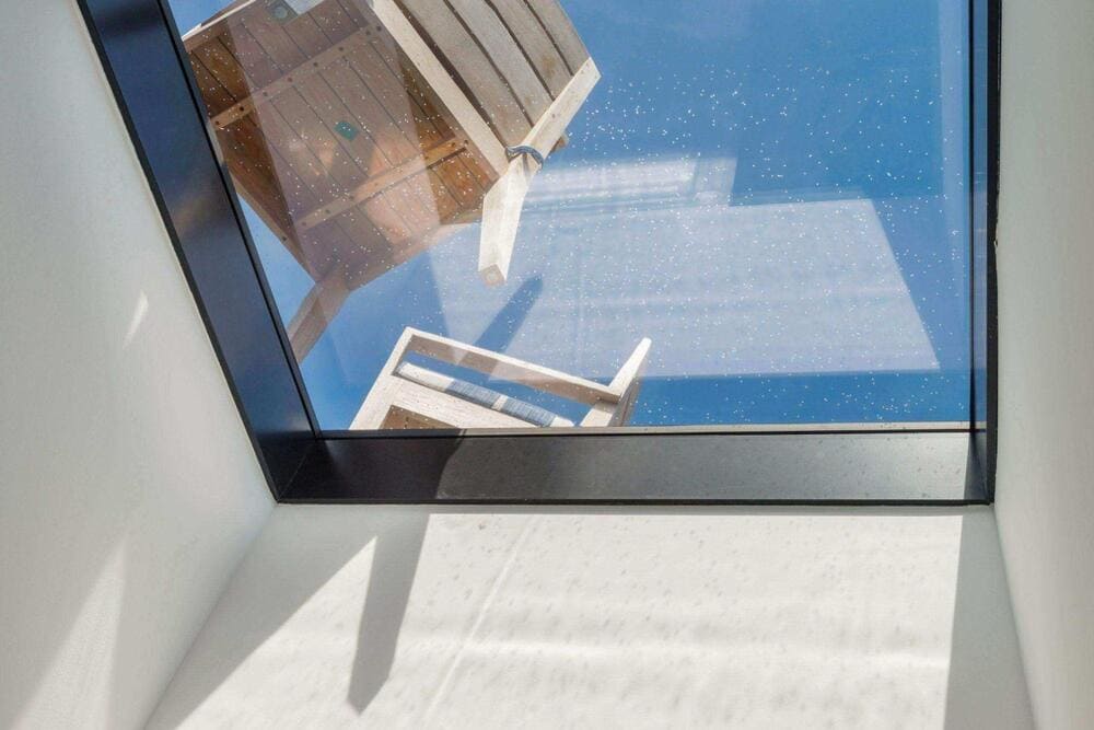 Interior view looking up through a modern flat skylight on a sunny day.