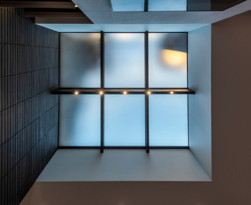 Looking straight up at a six-panel SkyFloor Series 1000 walkable skylight with black I-rafters and satin anti-slip glass from the living room below