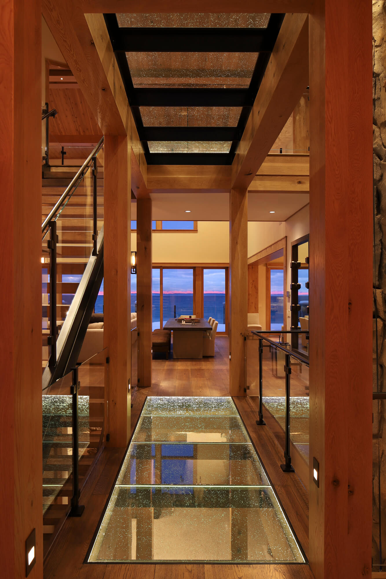 Timber-framed hallway crossing a structural glass floor bridge with Seeded Organic anti-slip panels, the second glass floor visible overhead